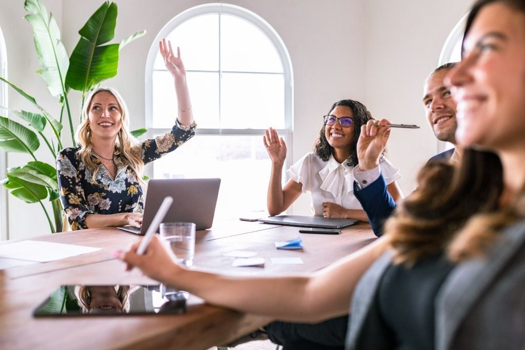 Diverse people in a meeting raising hands