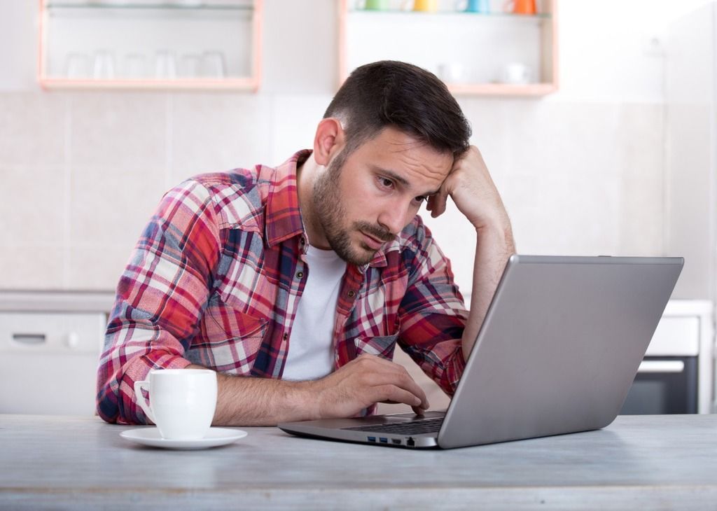 Man with laptop looking frustrated