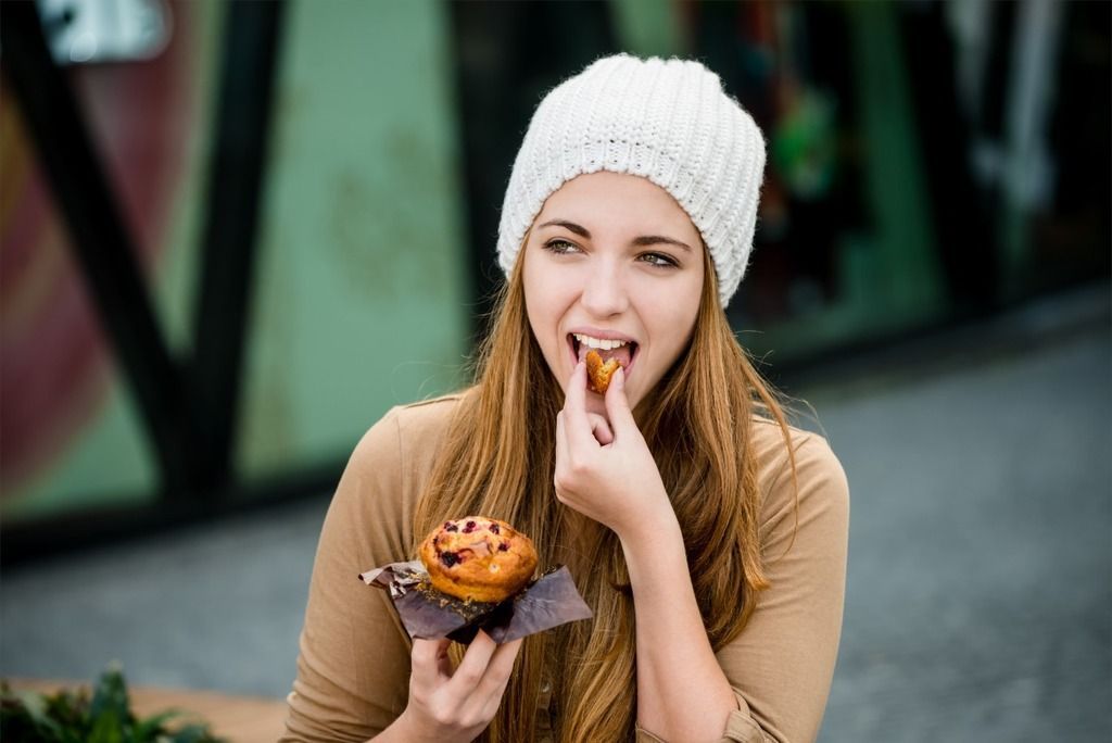 Woman brown shirt eating muffin