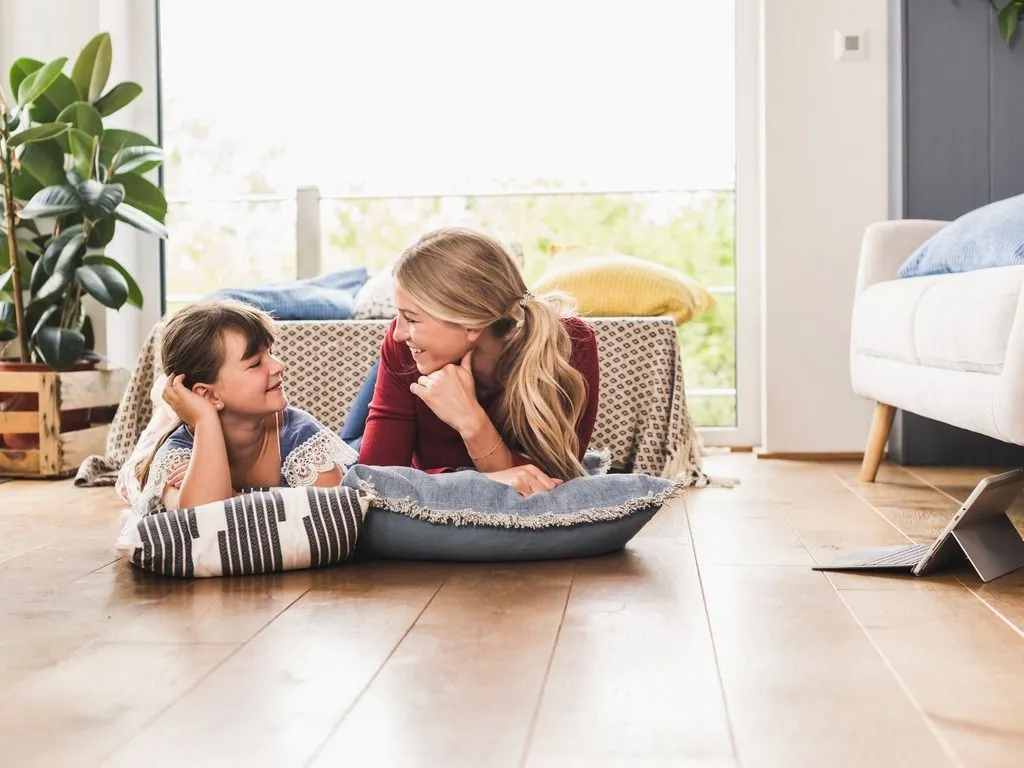 Mother and child lying on the floor at home smiling