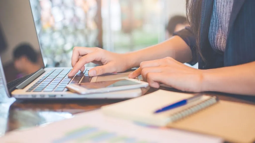 Hands of woman working at home on laptop with FaceReader